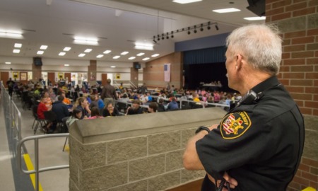 school police debate: school security guard looks out over cafeteria full of students