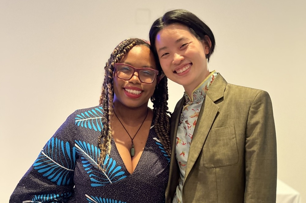 Asian-Black activism rekindled: A black woman and an Asian woman pose side by side, against a blank wall of a convention hall.