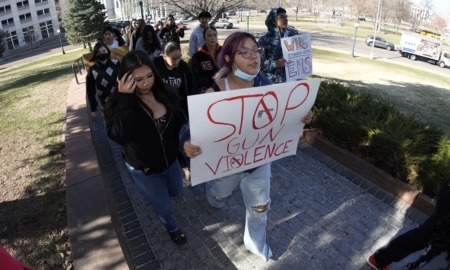 Denver school shooting suspect dead; parents push security: people marching down sidewalk with "Stop gun violence" sign