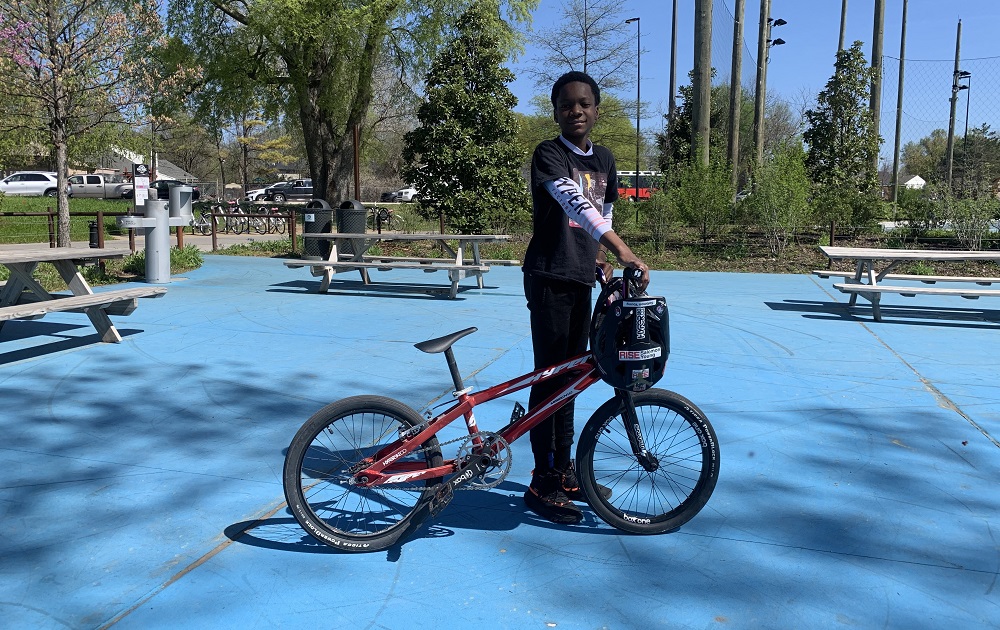 New BMX program teaches North Tulsa kids about bikes, racing and resilience: young black kid poses with his BMX bike outdoors