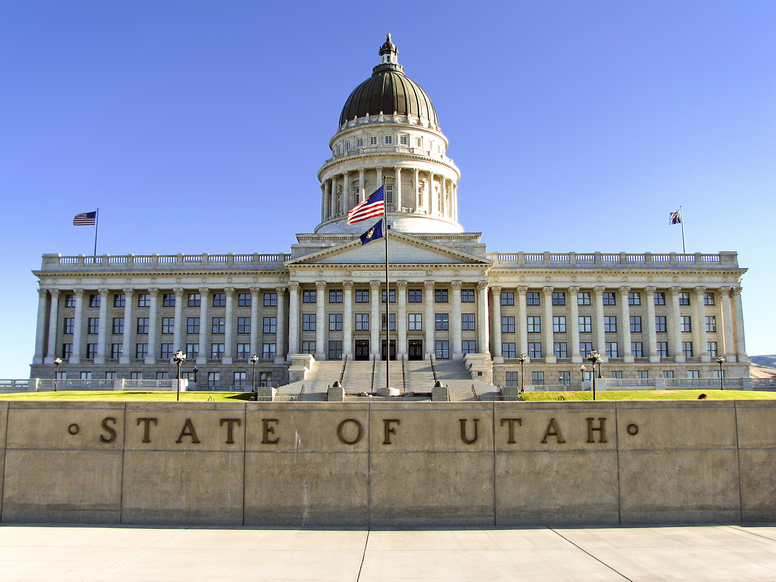 Utah child custody law: Utah state capitol — multi-storied, white, traditional architecture building with large, dark dome and American flag in front.